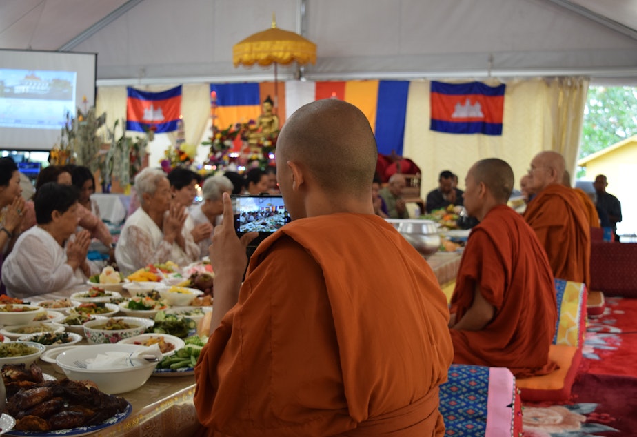 caption: Venerable Prenz Sa-Ngoun snaps photos of a Sunday Buddhist ceremony on his phone. He later posts his photos on Instagram.