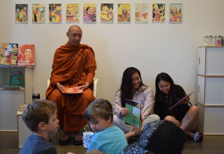 caption: Venerable Prenz and two members of the University of Washington Khmer Student Association, Melissa Ouk and Molica Perry, prepare for a bilingual book reading of “Colors of Cambodia” in Khmer and English.